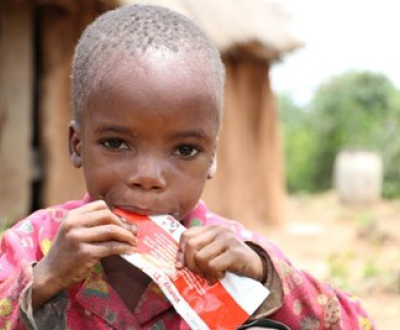 A malnourished child with a paper on his hand.