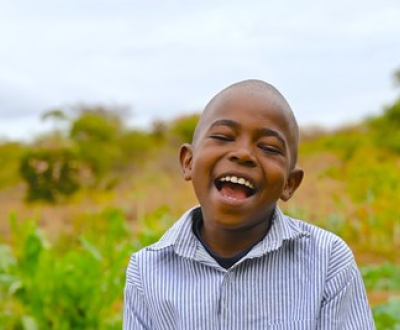 Boy from Kenya smiling in his family's World Vision-sponsored climate-smart agriculture farm