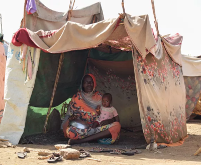 A child and a women inside a small hut which build by some cloths