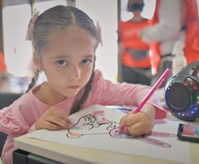 Girl from Ukraine drawing at a desk in a refugee centre in Romania