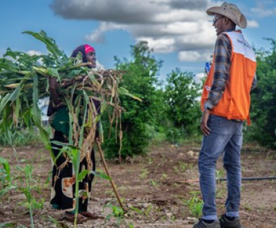 A guy talking to a woman holding corn plants in her hands