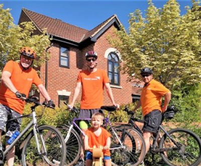 Family of four pose with bicycles in orange t-shirts to raise funds to protect children from coronavirus