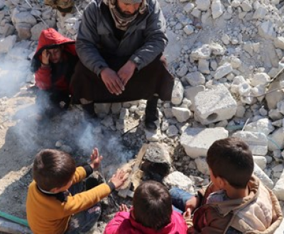 Father and two boys sit in rubble of a collapsed building after the earthquake in Syria.