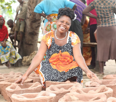 A women siting near some mud pots.