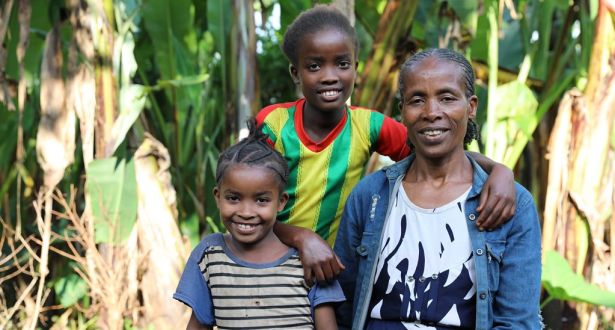 A mother from Ethiopia and her two daughters smiling at the camera