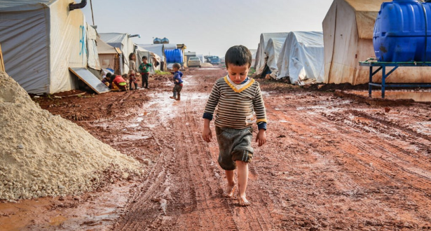 A boy walking the mud in an internally displaced camp in northwest Syria.