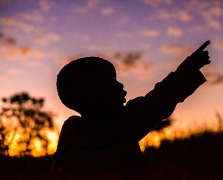 Child is pointing his hand on sky