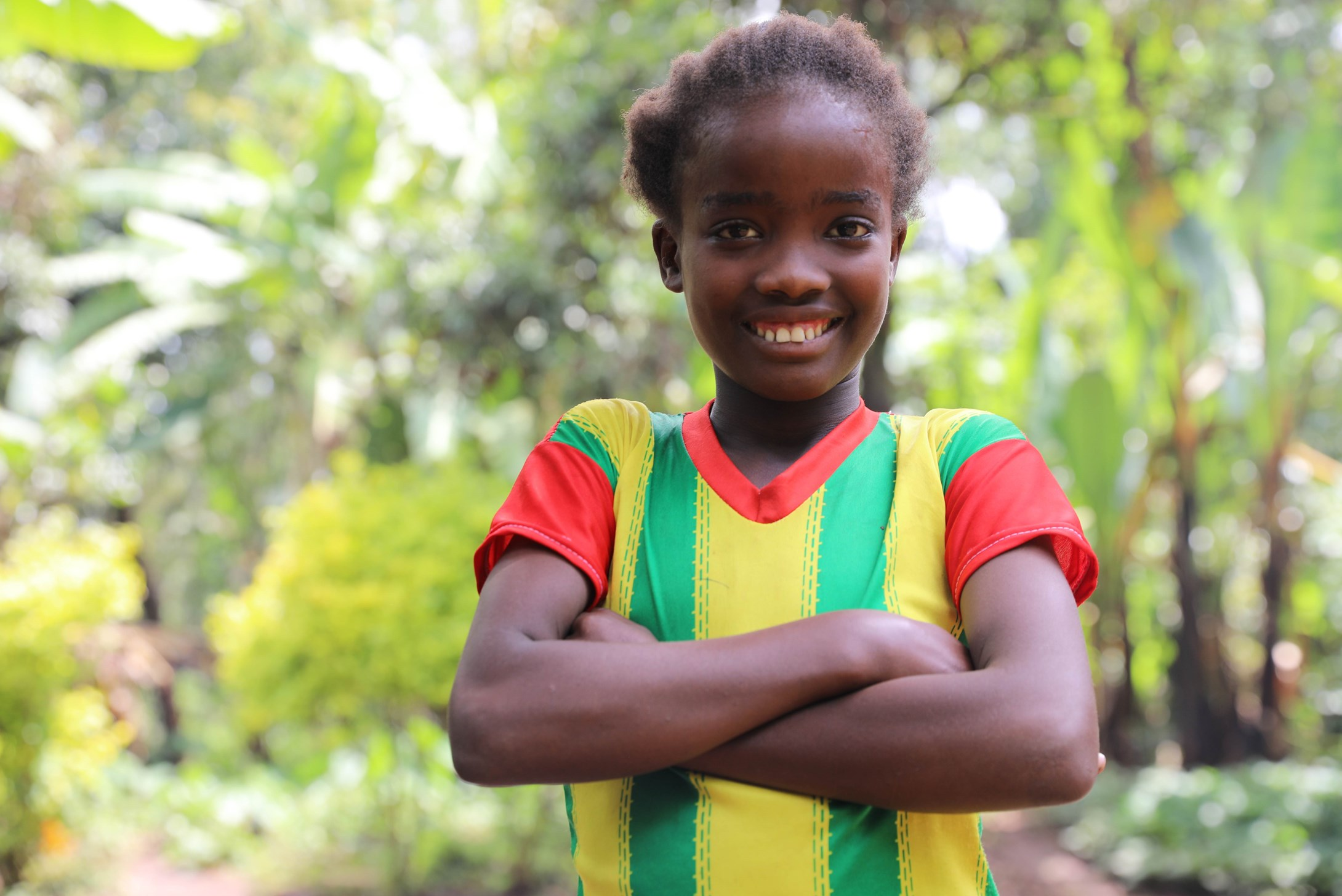 Girl from Ethiopia wearing a colourful t-shirt with her arms crossed