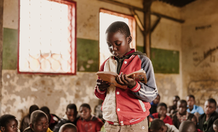 Boy from Malawi reading a book in his class