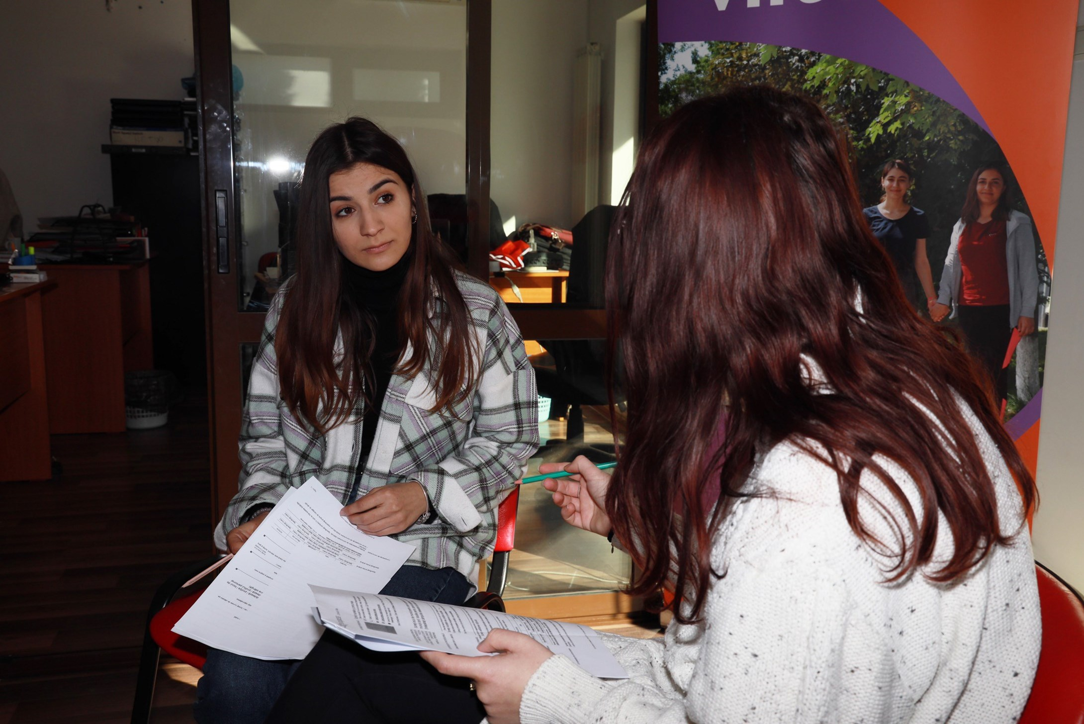 Girl from Romania talking to woman in foreground at a Ukrainian refugee camp in Romania