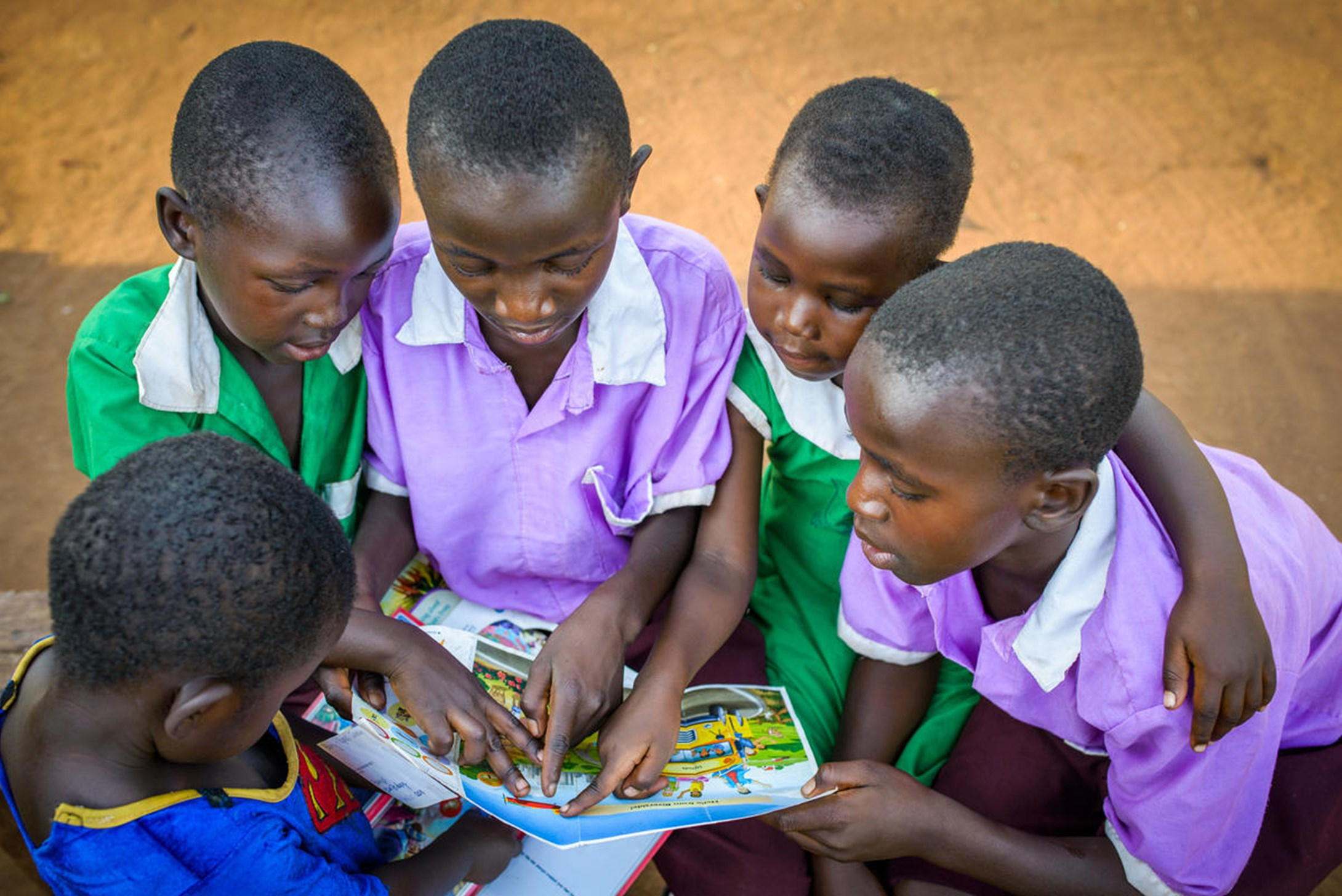 World Vision's sponsored child, Joshua, and his siblings look at his sponsor's cards