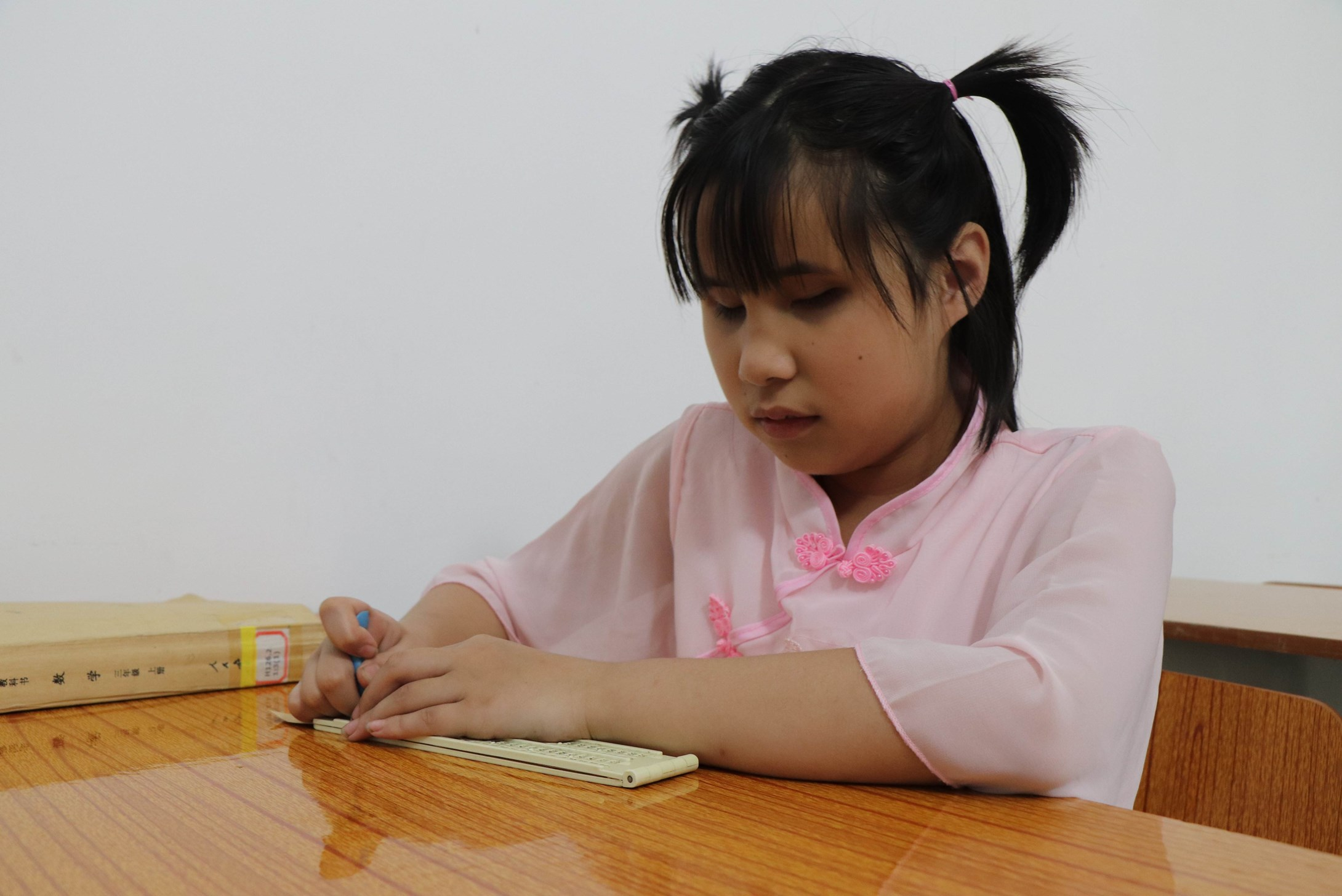 Schoolgirls from China sitting at a desk and writing on a piece of paper.