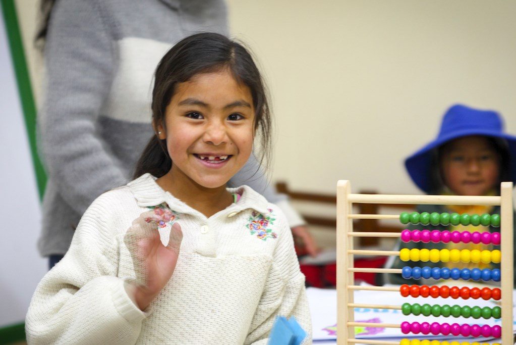 A Girl child is standing near an Abacus