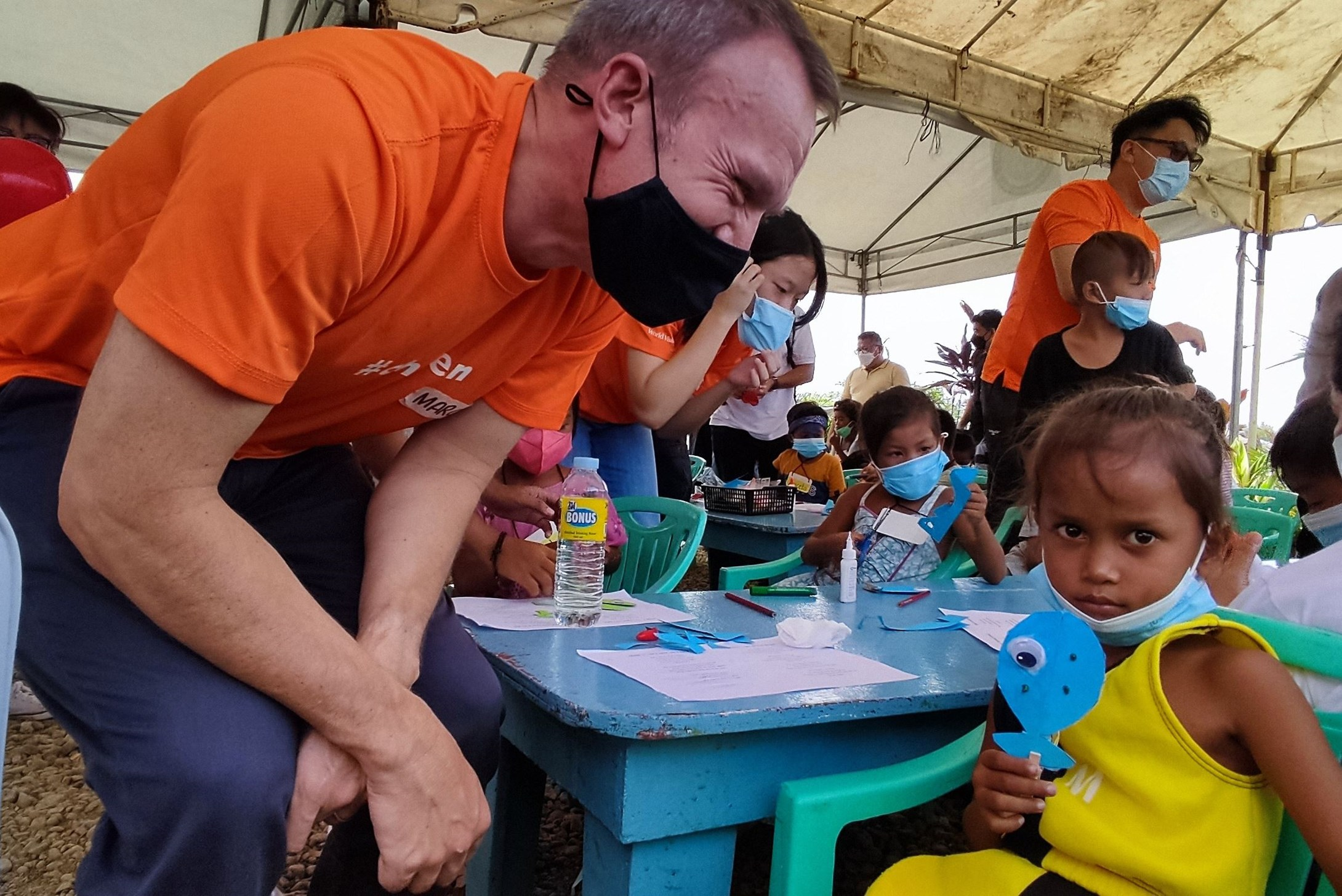 World Vision volunteer talking to a child in the Philippines