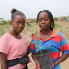 Sisters Julieta and Eularia holding up a plant pot with a crop they planted in their field farming school